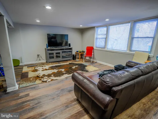 a living room with furniture kitchen view and a wooden floor