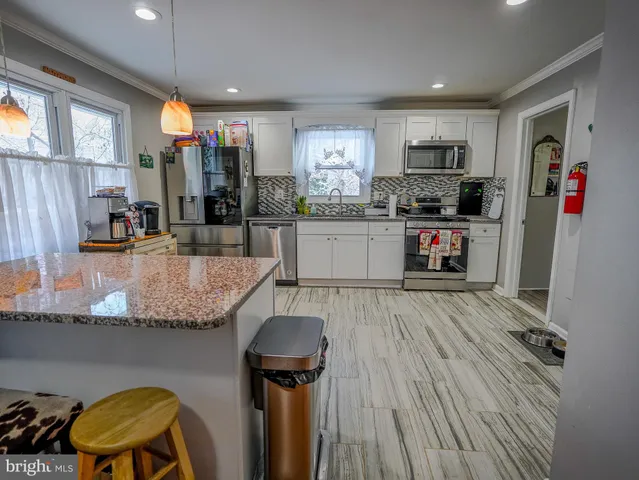 a kitchen with stainless steel appliances granite countertop a refrigerator a stove top oven a sink dishwasher and wooden cabinets with wooden floor