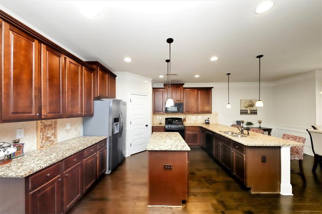 4058 Rosebay Way Southwest Conyers, GA 30094 - Photo 16 of 55 a large kitchen with stainless steel appliances kitchen island granite countertop a sink stove and refrigerator