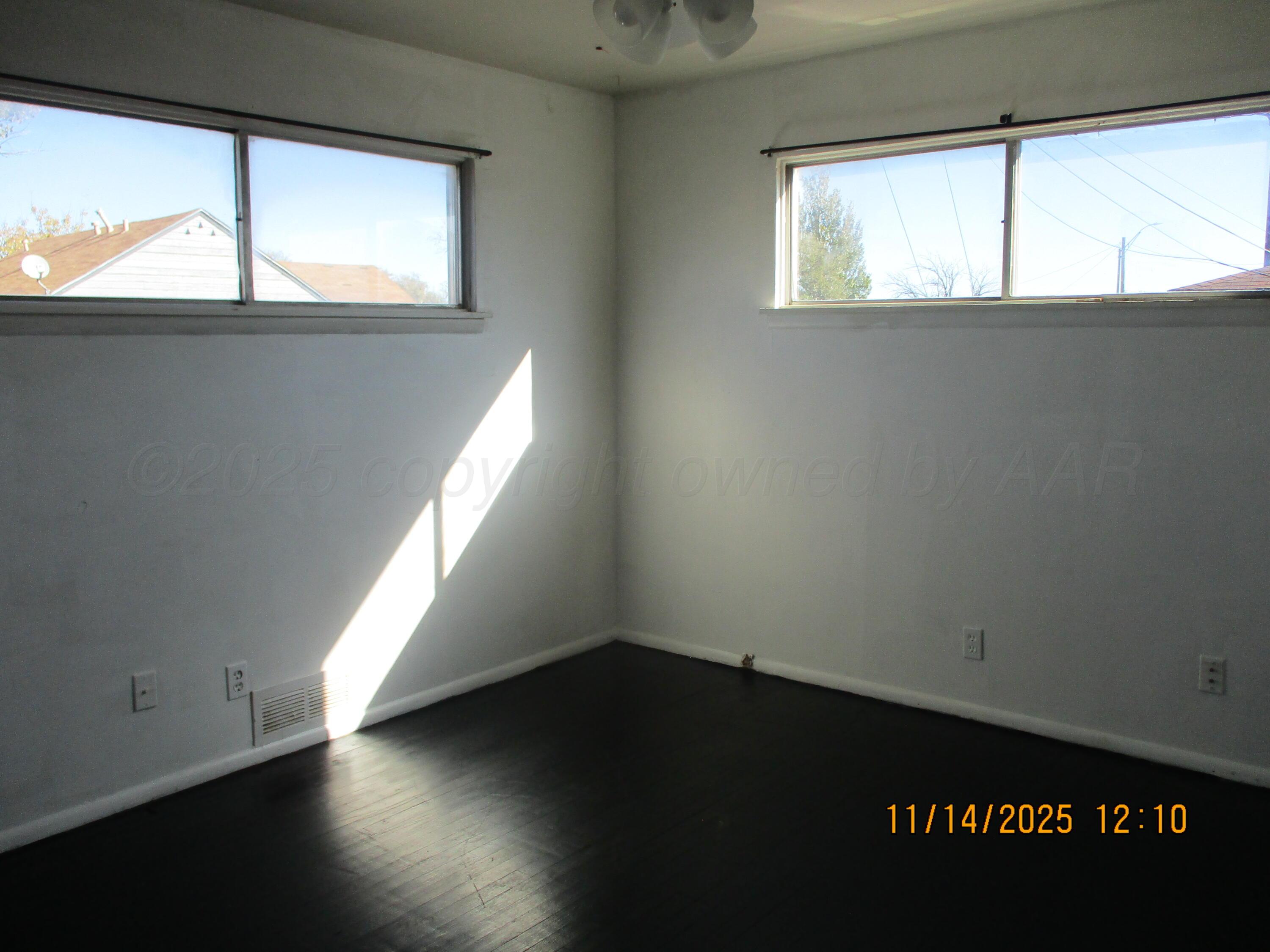 211 Southwest 34th Avenue Amarillo, TX 79109 - Photo 5 of 10 an empty room with wooden floor and windows