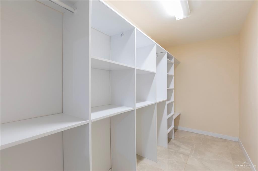 2001 Quail Lane Mission, TX 78572 - Photo 16 of 28 Custom built-in white shelving system featuring multiple storage compartments and a hanging rod