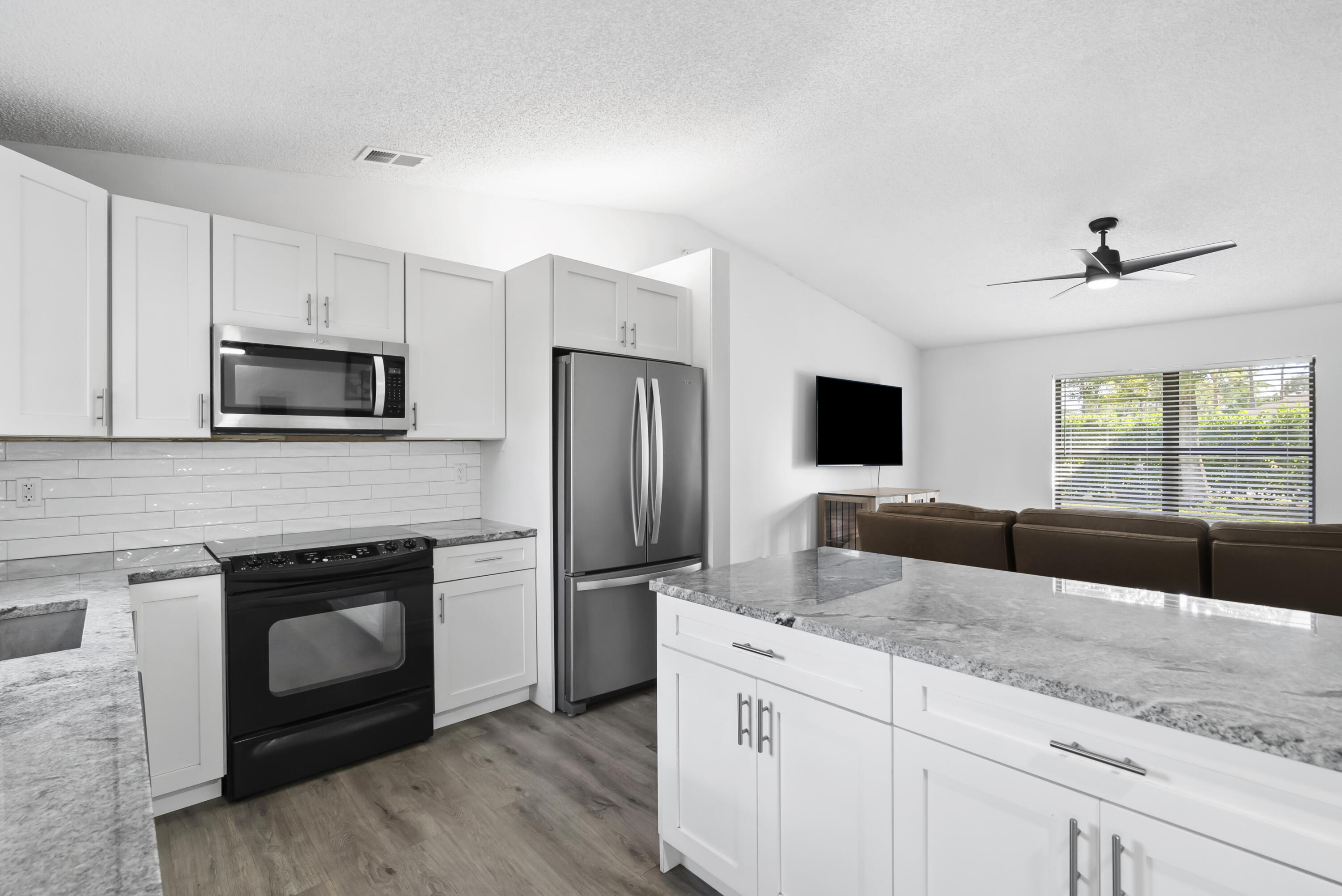 17493 41st Road North The Acreage, FL 33470 - Photo 11 of 45 a kitchen with granite countertop a sink stainless steel appliances and white cabinets