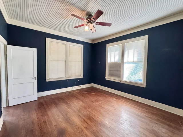 an empty room with windows and ceiling fan