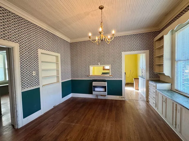 a view of a room with wooden floor and kitchen view