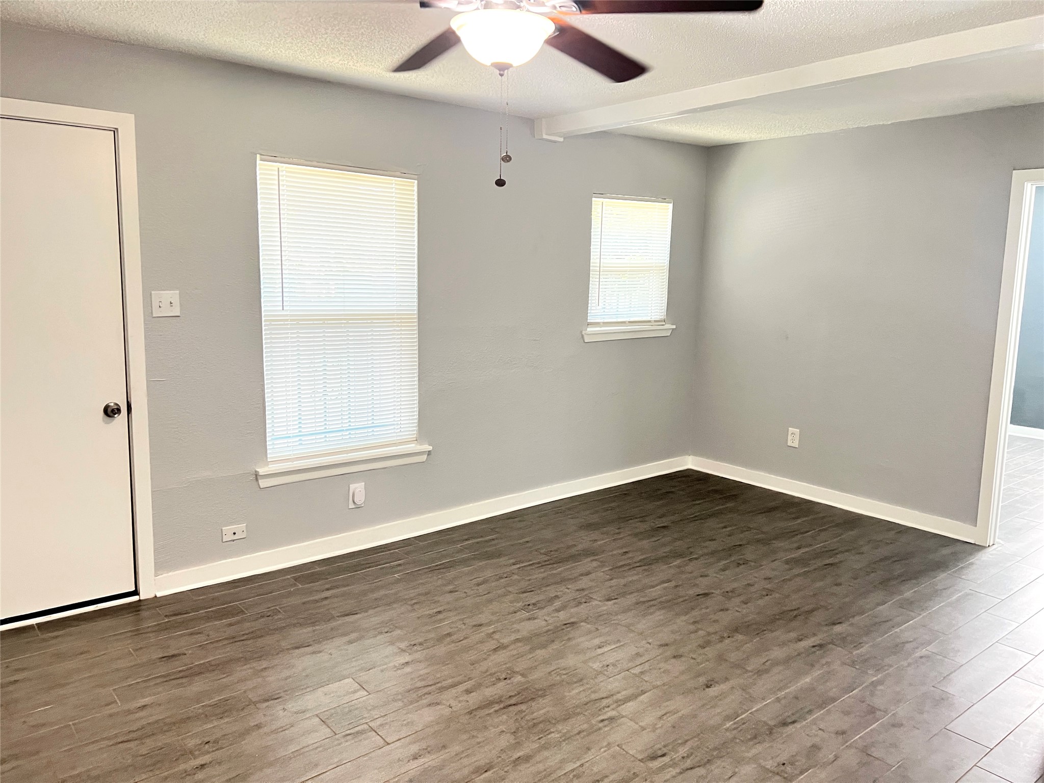 an empty room with wooden floor and windows