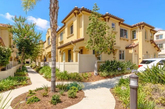 a front view of a multi story residential apartment building with yard and parking