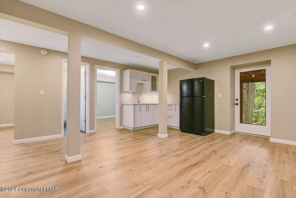159 Manchester Drive Bushkill, PA 18324 - Photo 32 of 68 a view of an empty room with wooden floor and a kitchen