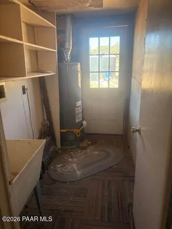 a room with water heater and wooden cabinets