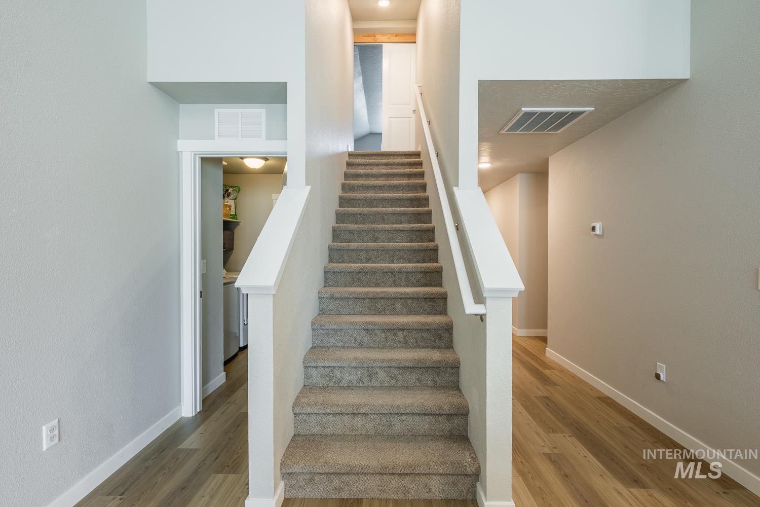 12623 Shadow Peak Street Caldwell, ID 83607 - Photo 42 of 50 Carpeted staircase with white balusters and handrail, neutral wall tones, wood-finish flooring, and integrated lighting