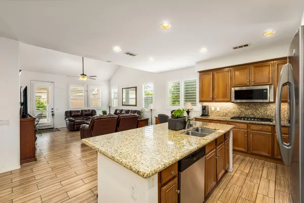 a kitchen with stainless steel appliances granite countertop a refrigerator and a stove top oven