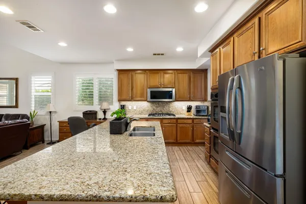a kitchen with stainless steel appliances granite countertop a kitchen island hardwood floor sink and stove