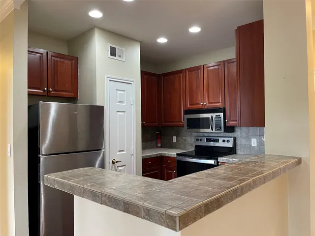 a kitchen with stainless steel appliances a refrigerator sink stove microwave and cabinets