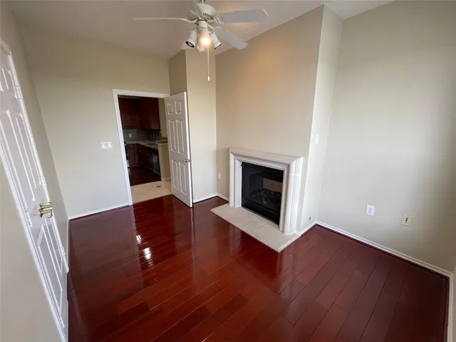 an empty room with wooden floor fireplace and a window