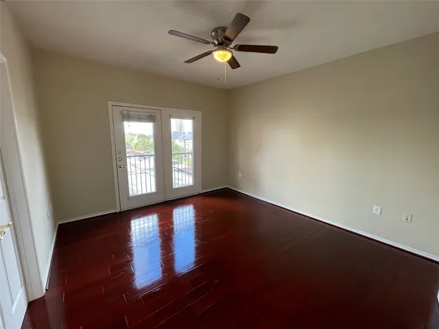 an empty room with wooden floor and windows with curtains
