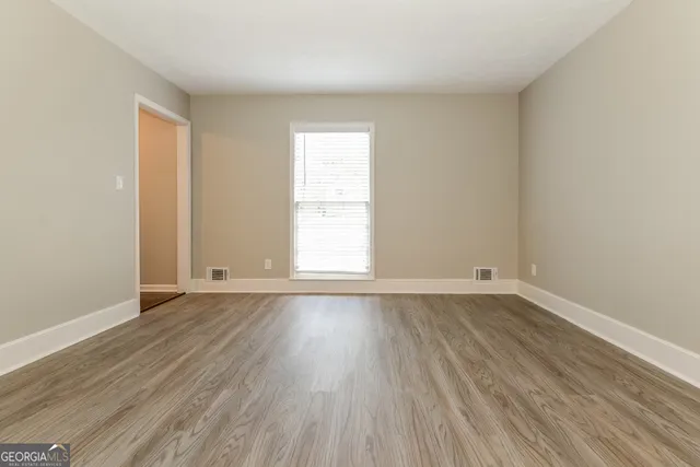 an empty room with wooden floor and window