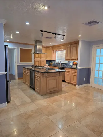 a large kitchen with stainless steel appliances granite countertop a stove top oven a sink dishwasher and cabinets