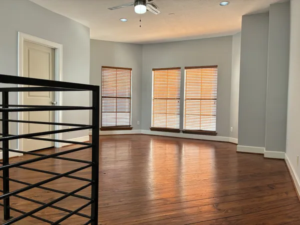 a view of an empty room with window and wooden floor