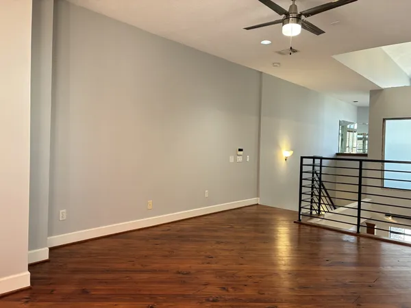 an empty room with wooden floor fan and windows