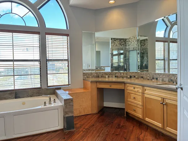 a spacious bathroom with a granite countertop tub a double vanity sink a large mirror and a window