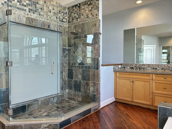 a bathroom with a granite countertop sink a mirror and shower