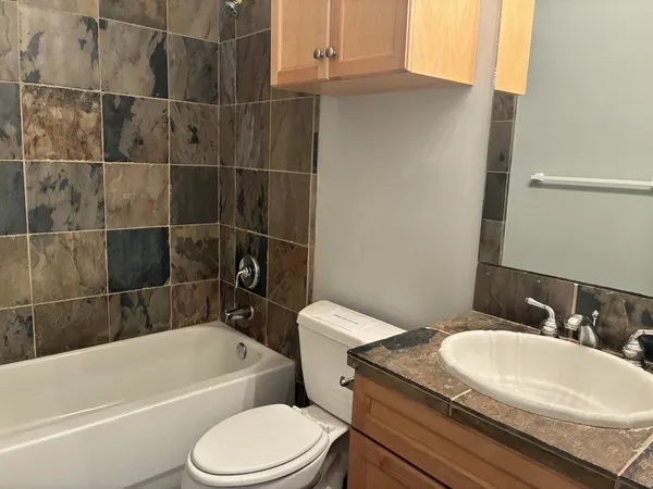 a bathroom with a granite countertop toilet sink and bathtub