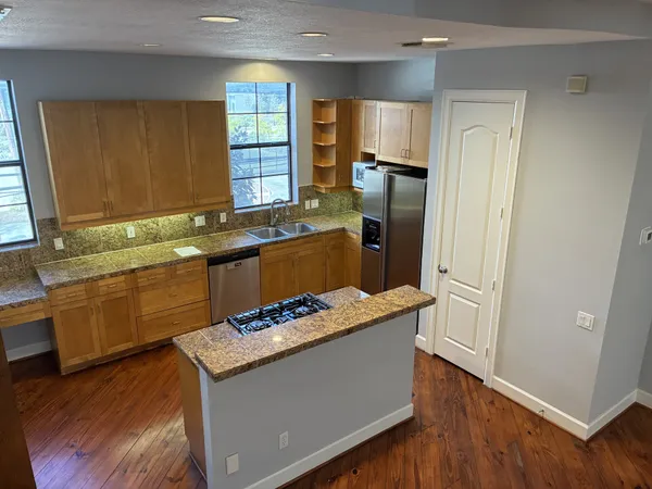 a kitchen with granite countertop stainless steel appliances a sink stove refrigerator and cabinets
