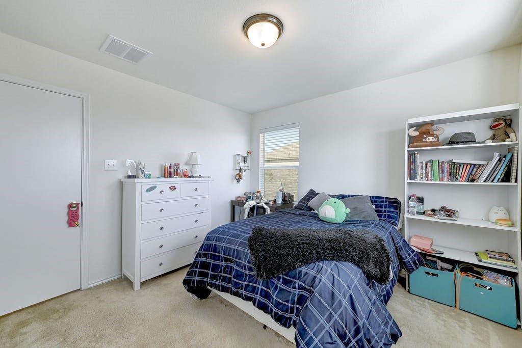13916 Inaugural Street Manor, TX 78653 - Photo 22 of 28 Comfortable bedroom with ample natural light and a soft carpeted floor.