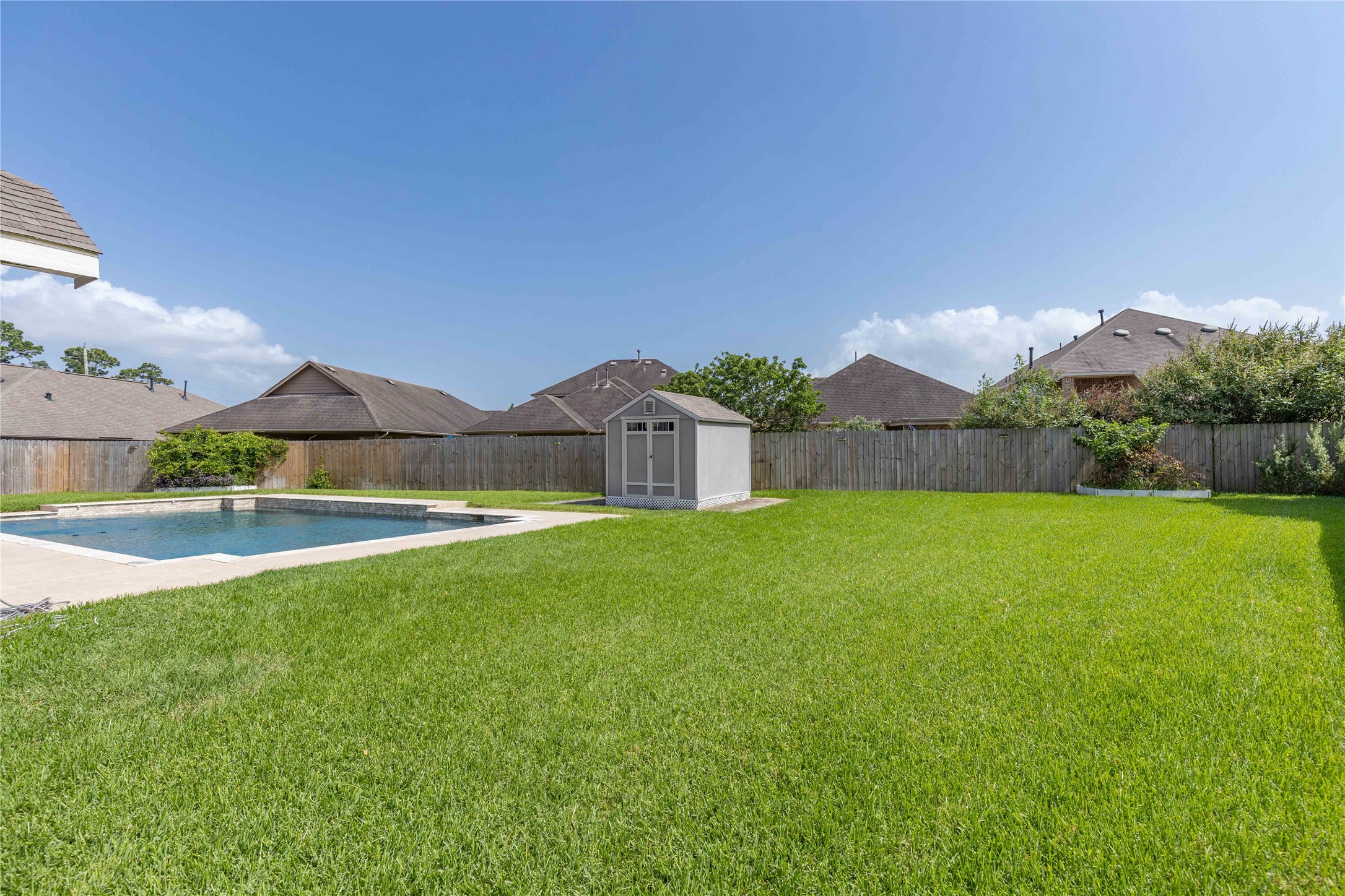 17206 Upper Ridge Lane Humble, TX 77346 - Photo 45 of 50 Spacious backyard with lush green lawn, a large swimming pool, and a storage shed, all enclosed by a wooden fence for privacy.
