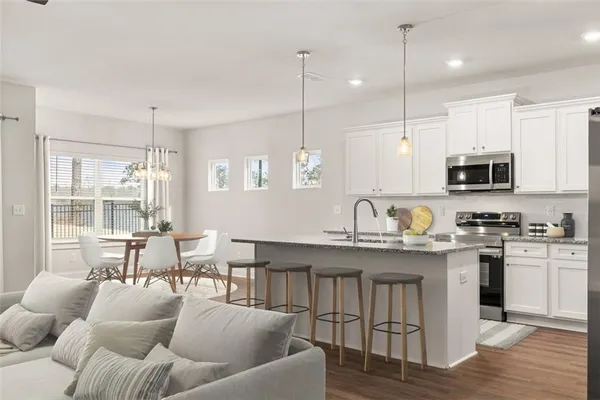 a open kitchen with stainless steel appliances granite countertop a stove a sink a center island a dining table and chairs