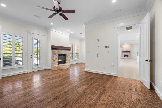 a view of a livingroom with wooden floor a ceiling fan and windows