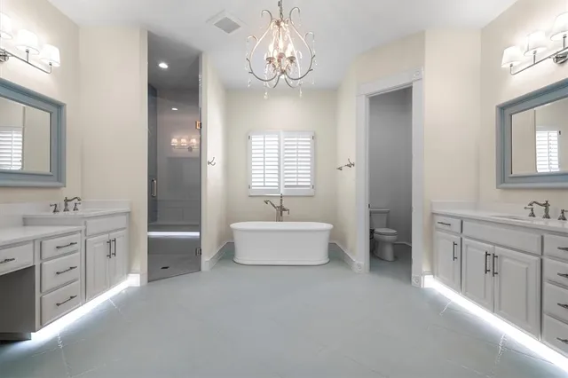a spacious en suite bathroom with a tub double sink and mirror