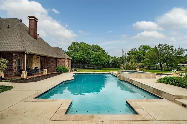 a view of swimming pool with lawn chairs and plants