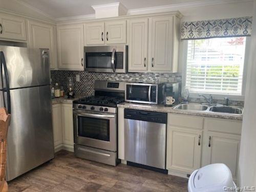 1661 Old Country Road, Unit 49 Riverhead, NY 11901 - Photo 8 of 11 a kitchen with stainless steel appliances a stove microwave and refrigerator