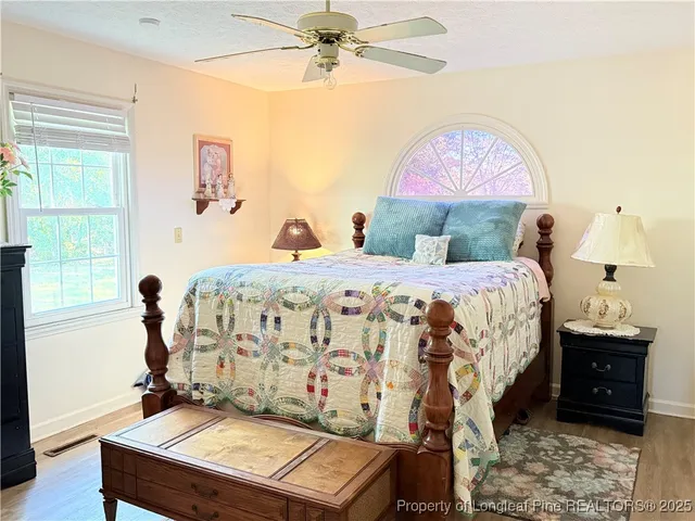 a view of a bedroom with wooden floor and ceiling fan