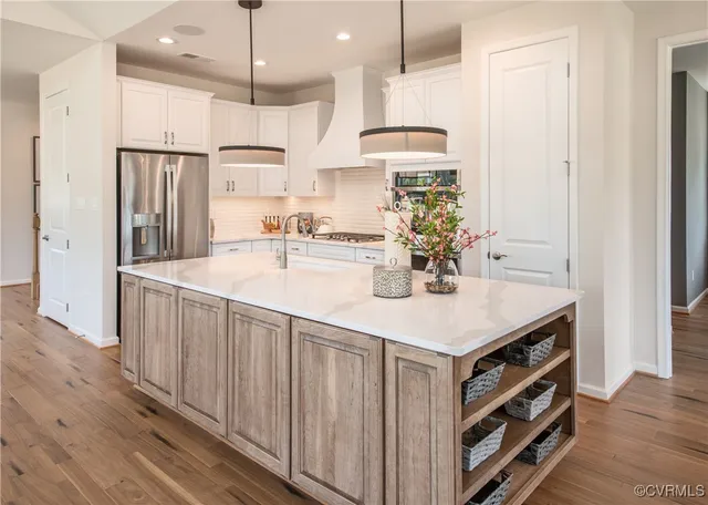 a kitchen with stainless steel appliances a center island wooden floor and white cabinets