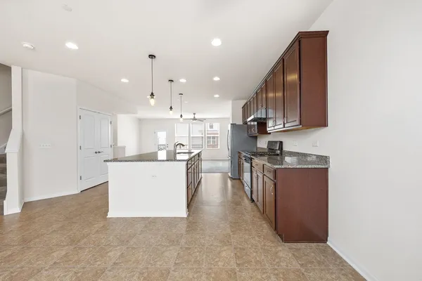 a large kitchen with stainless steel appliances granite countertop a large counter top a sink dishwasher a refrigerator and cabinets with wooden floor