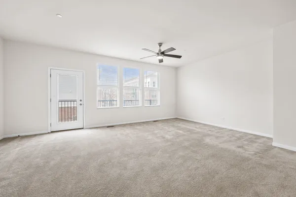 an empty room with chandelier fan and windows