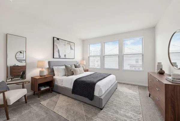a spacious bedroom with a bed a couch and a flat tv screen on dresser