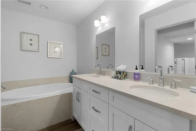 a bathroom with a tub double sink and mirror