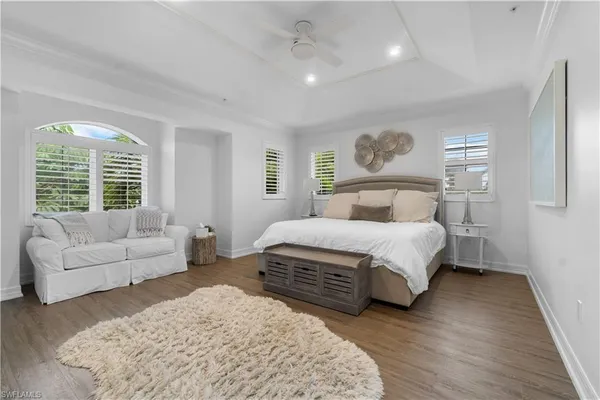 a bedroom with a large bed couch and windows