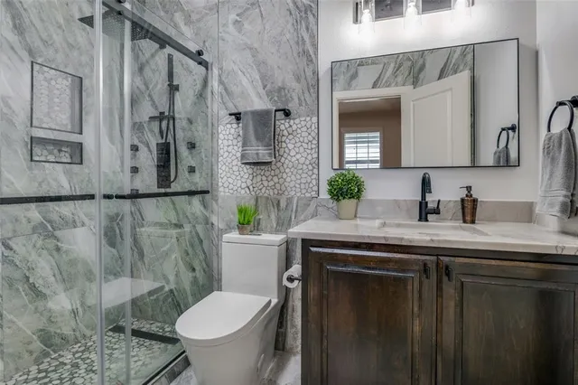 a bathroom with a granite countertop toilet sink and mirror