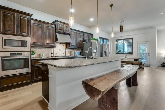 a kitchen with stainless steel appliances granite countertop wooden cabinets a stove and a sink