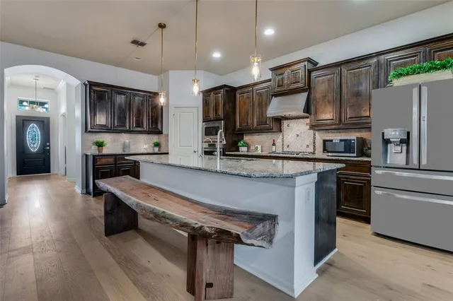 a kitchen with stainless steel appliances granite countertop a refrigerator a stove and a sink