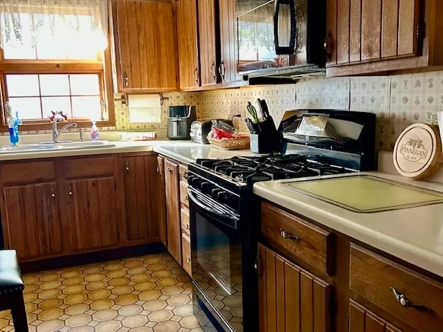 a kitchen with stainless steel appliances granite countertop a stove a sink and a microwave