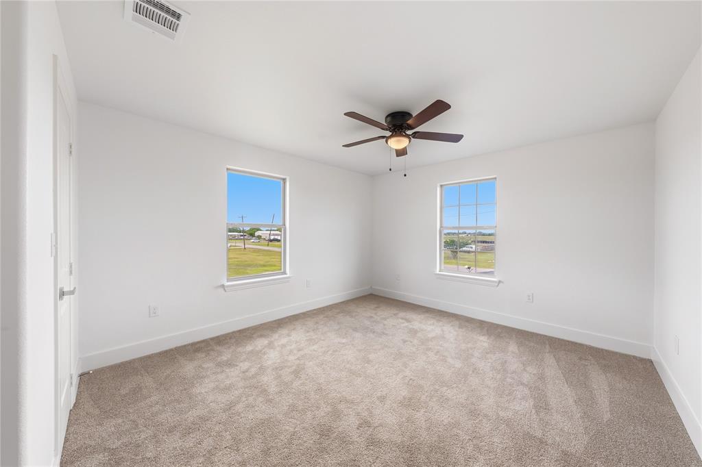 1128 Newton Road Ferris, TX 75125 - Photo 21 of 28 Spacious room featuring neutral carpeting, white walls, two windows, a ceiling fan, and white trim