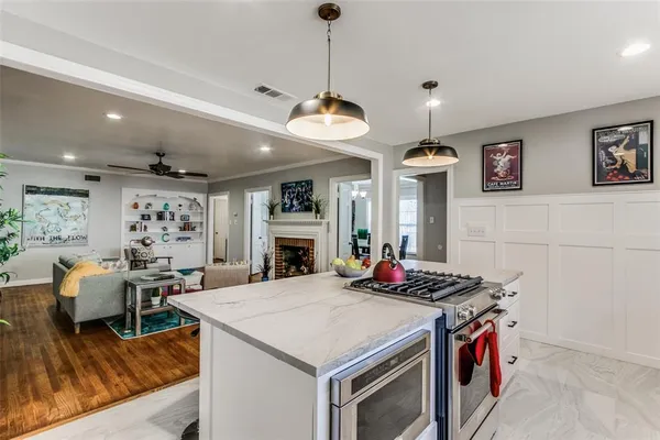 a kitchen with stainless steel appliances kitchen island granite countertop a dining table chairs and a refrigerator