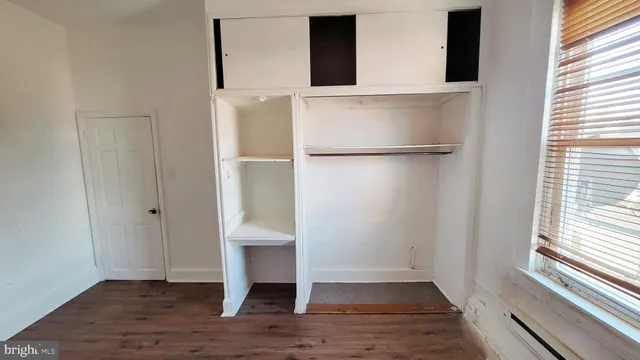 a view of empty room with wooden floor and window