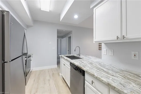 a kitchen with granite countertop a sink stove and refrigerator