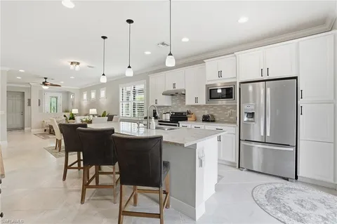 a kitchen with stainless steel appliances granite countertop a refrigerator a sink dishwasher a stove and white cabinets with wooden floor