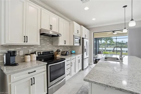 a kitchen with stainless steel appliances granite countertop a stove a sink and white cabinets